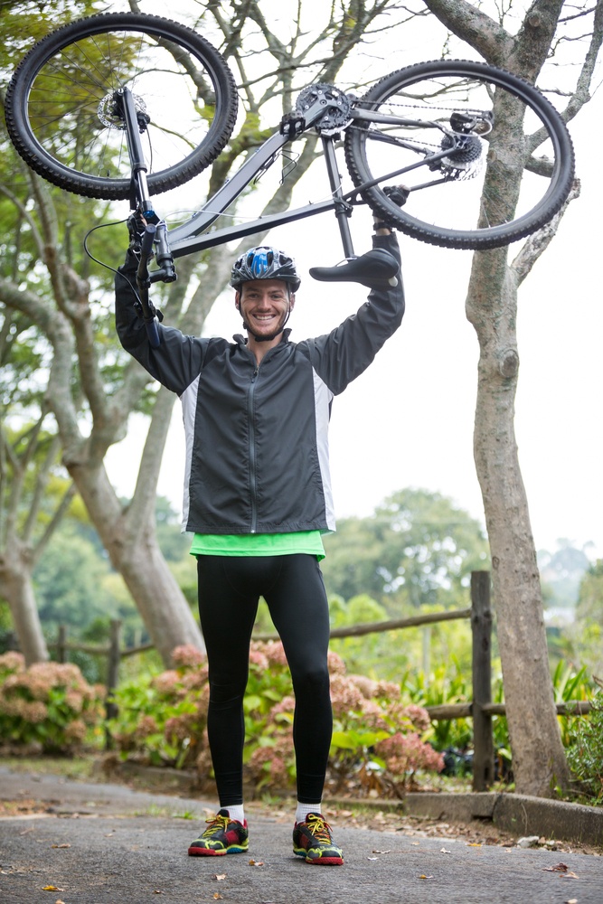 Portrait of male cyclist carrying mountain bike in park